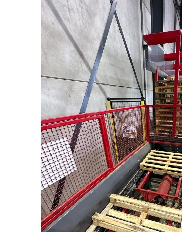 De rode geautomatiseerde sorteerlijn van Zoethout Pallets, met pallets op de rollenbaan